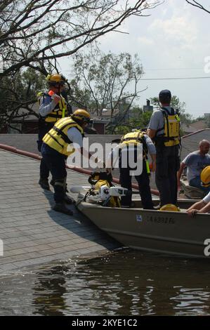 Hurrikan Katrina, New Orleans, LA, 31. August 2005 – Ein FEMA Urban Search and Rescue (US&R)-Team der Missouri Task Force 1 transportiert Ausrüstung aus einem Boot auf ein Dach, während sie sich darauf vorbereiten, diesen Dachboden nach Überlebenden und Verstorbenen zu durchsuchen. New Orleans ist überflutet und wird infolge des Hurrikans Katrina evakuiert. Stockfoto