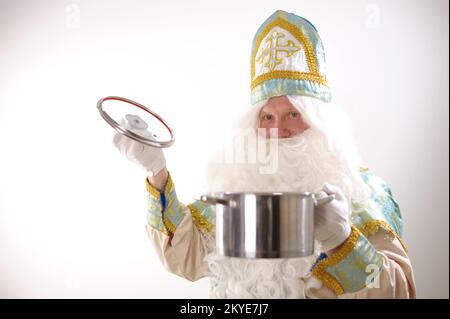 Sinterklaas-Porträt. USA auf weißem Hintergrund. Holländischer Weihnachtsmann St. Nicholas weihnachten Neujahr St. Nicholas mit einem Topf in den Händen bereitet Silvester-Essen für Weihnachten vor Stockfoto