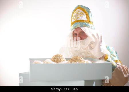 Sinterklaas-Porträt. USA auf weißem Hintergrund. Holländischer Weihnachtsmann St. Nikolaus weihnachten Neujahr St. Nikolaus hat eine große blaue Box eröffnet, sie ist leer, es gibt ein Geschenk darin Neujahr kommt Stockfoto