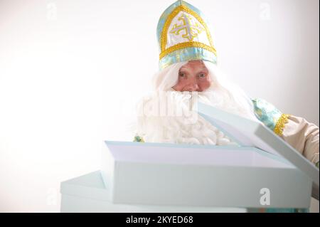 Sinterklaas-Porträt. USA auf weißem Hintergrund. Holländischer Weihnachtsmann St. Nikolaus weihnachten Neujahr St. Nikolaus hat eine große blaue Box eröffnet, sie ist leer, es gibt ein Geschenk darin Neujahr kommt Stockfoto