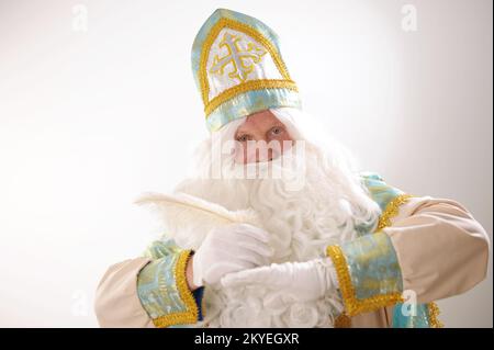 Sinterklaas-Porträt. USA auf weißem Hintergrund. Der niederländische Weihnachtsmann St. Nikolaus weihnachten Neujahr in den Händen von St. Nicholas, ein weißer Stift, denkt, was er schreiben soll, um Wünsche zu erfüllen Stockfoto