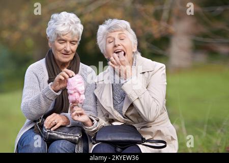 Immer noch unser Lieblingsgeschenk. Zwei ältere Frauen essen Zuckerwatte zusammen. Stockfoto