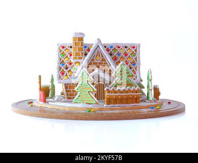 Weihnachten Lebkuchenhaus im Schnee. Wunderschönes Lebkuchenhaus mit Kamin, Сhristmas Bäumen und Zaun. darstellung des 3D-Renderings auf weiß isoliert. Stockfoto