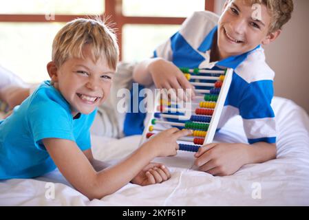 Alte Mathematik. Porträt von zwei jungen Geschwistern, die mit einem Abakus spielen. Stockfoto