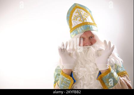 Zeigt sich gut mit zwei Händen mit weißen Handschuhen Sinterklaas Portrait USA auf weißem Hintergrund niederländischer Weihnachtsmann St. Nikolaus weihnachten Neujahr sly Blue Eyes üppiger weißer Bart und Schnurrbart Stockfoto