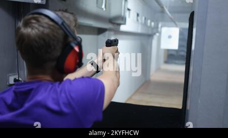 Ein Mann schießt auf das Ziel mit einer Pistole im Schießstand. Stockfoto