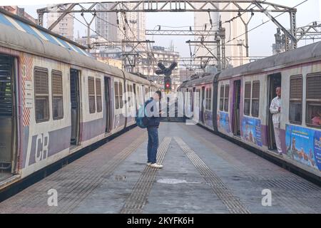 Ein stationärer Zug (l) und ein Zug (r), die beide die Central Line am Chhatrapati Shivaji Maharaj Terminus (CSMT), Mumbai, Indien, anfahren Stockfoto