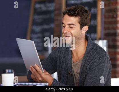 Touchscreen-Technologie. Ein junger Mann, der in einem Café an einem digitalen Tablet arbeitet. Stockfoto