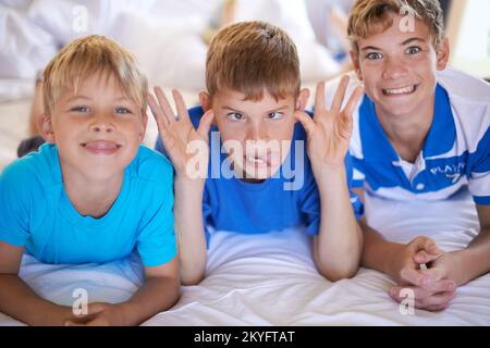 Jungs werden Jungs sein. Drei Brüder ziehen lustige Gesichter vor die Kamera. Stockfoto