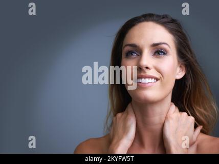 Sie erhellt einen Raum mit ihrem Lächeln. Eine attraktive junge Frau, die im Studio glücklich lächelt. Stockfoto