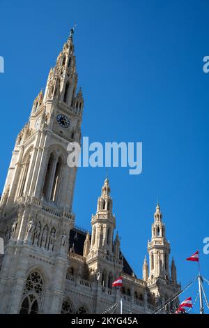 Wien, Österreich - 22. September 2022: Das Wiener Rathaus unter blauem Himmel mit österreichischen Flaggen im Vordergrund Stockfoto