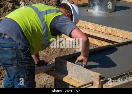 Biloxi, MS, 6. Mai 2015 - Ein Bauarbeiter von Oscar Renda Contracting beendet die Betonvorbereitung für den Austausch von Aufkantung und Abflussrinnen nach der Installation neuer Wasser- und Abwasserleitungen unter der 8.. Straße in Biloxi, MS. Die Wiederherstellung der Wasser- und Kanalisationsinfrastruktur von Biloxi ist Mississippis größtes FEMA-Projekt zur öffentlichen Unterstützung im Zusammenhang mit dem Wiederaufbauprogramm für den Hurrikan Katrina. Stockfoto