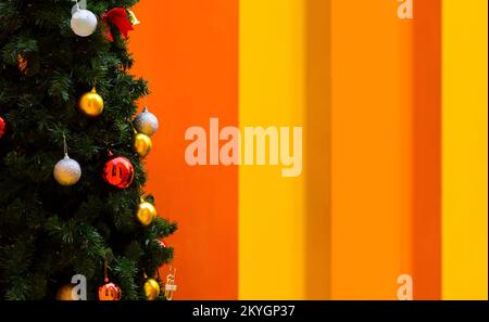 Weihnachtsbaum mit farbenfrohem Fokus und verschwommenen Kugeln mit farbenfrohem Hintergrund. Stockfoto