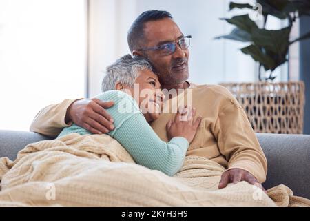 Seniorenpaar, Umarmung und Liebe auf der Wohnzimmercouch, denken über die Zukunft, Lebensversicherung und Glück im Ruhestand zusammen nach. Mann und Frau Stockfoto