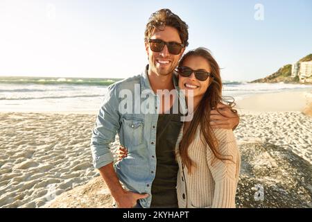 Strandurlaub ist der beste. Porträt eines liebevollen jungen Paares, das am Strand steht und sich hält. Stockfoto