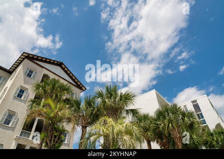 Destin, Florida - niedriger Blickwinkel auf mehrstöckige Häuser mit Palmen vor dem Hotel. Strandhäuser mit Balkonen vorne unter dem Himmel. Stockfoto
