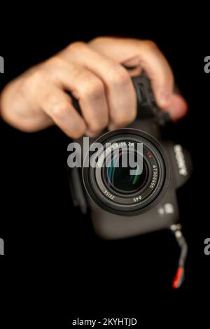 Fotograf Macht Selbstporträt. Verwenden einer spiegellosen Kamera zum Aufnehmen eines Fotos. Sony A7 IV, Zeiss 55mm. Selektiver Fokus auf Objektiv. Direkt in eine Kamera Stockfoto