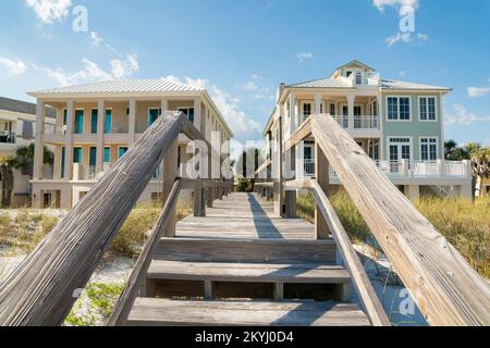 Destin, Florida - Treppen auf einer hölzernen Fußgängerbrücke über den Sanddünen vor den Strandhäusern. Pfad mit Handläufen zwischen den Gebäuden w Stockfoto