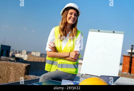 Junge weibliche Bau spezialisierte Techniker Blueprints auf Baustelle Stockfoto