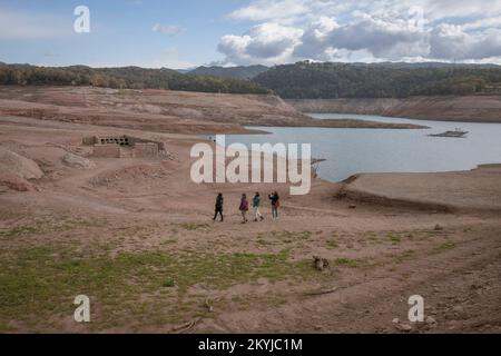 Sau-Reservoir bei 30 % seines Fassungsvermögens. Vier Frauen besuchen den neuen Friedhof von Sant Romà de Sau, der heute aufgrund des Wassermangels im Sumpf von Sau, Vilanova de Sau, Spanien, am 29. November 2022 entdeckt wurde. © Joan Gosa 2022/Alamy Stockfoto