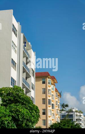 Eine Reihe moderner und traditioneller Apartments in Miami, Florida. Es gibt ein Gebäude mit beigefarbener Fassade und Erkerfenstern in der Mitte von zwei weißen modernen Stockfoto