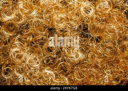 Goldenes metallisches Engelhaar, Hintergrund, von oben. Gelocktes goldenes Lametta-Engelhaar, aus sehr dünnem Kupferdraht. Weihnachtsdekoration. Stockfoto