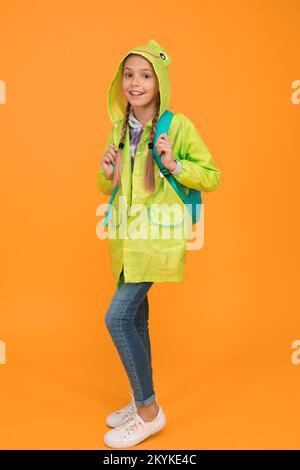 Sie ist cool. Glückliches kleines Kind Tragen Sie eine modische Regenjacke auf gelbem Hintergrund. Lächelndes Kleinkind mit Herbstlook. Ein kleines Mädchen, bereit für eine regnerische Reise Stockfoto