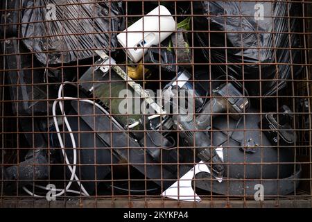 Stapel von gemischten schmutzigen Elektronikschrottgeräten in einem Metallkäfig in einer Sammelstelle für Elektronikschrott. Stockfoto