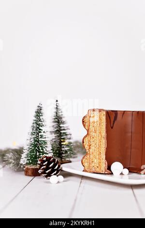 Traditionelle deutsche geschichtete Winterkuchen genannt "Baumkuchen" glasiert mit Schokolade, umgeben von saisonalen Dekoration Stockfoto