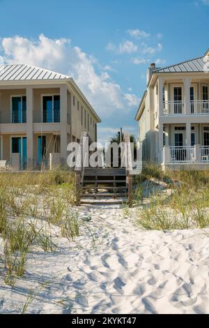 Destin, Florida - Treppen einer hölzernen Fußgängerbrücke über die Sanddünen vor den Strandhäusern. Fußgängerbrücke zwischen den beiden Strandhäusern mit Terra Stockfoto