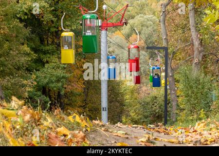 Farbenfrohe Kabinen im Erholungspark der Stadt Kharkiv mit Wanderweg und herbstfarbenen Blättern. Ansicht aus niedrigem Winkel Stockfoto