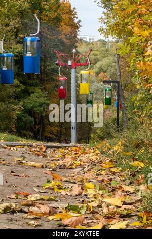 Farbenfrohe Kabinen im Erholungspark der Stadt Kharkiv mit Wanderwegen, die von herbstlichen Blättern bedeckt sind Stockfoto