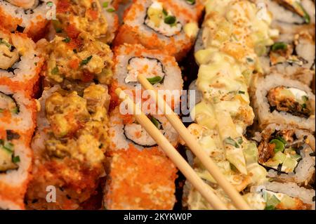 Eine Reihe verschiedener Rollentypen in einer Schachtel. Blick von oben auf verschiedene Portionen vegetarischer und Fischbrötchen. Nahaufnahme, selektiver Fokus. Stockfoto