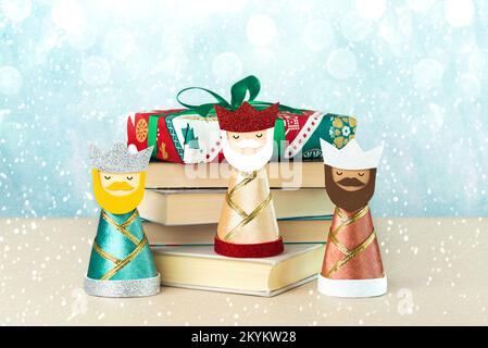 Die drei Weisen mit Büchern, Schneeflocken und weihnachtslichtern auf blauem Hintergrund. Konzept für Reyes Magos Day, drei Weisen Stockfoto
