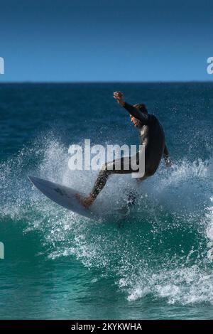 Spektakuläre Surfaktion als männlicher Surfer reitet auf einer Welle im Fistral in Newquay in Cornwall in England in Großbritannien. Stockfoto