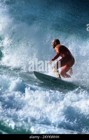 Spektakuläre Surfaktion als männlicher Surfer reitet auf einer Welle im Fistral in Newquay in Cornwall in England in Großbritannien. Stockfoto