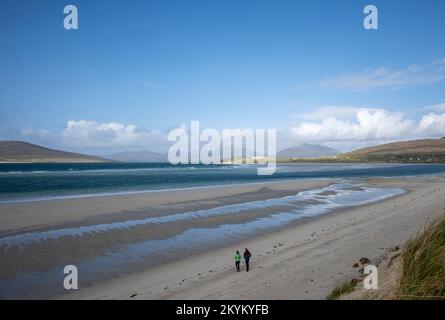 Zwei einsame Leute, die am Sandstrand von Seilebost auf der Insel Harris spazieren Stockfoto