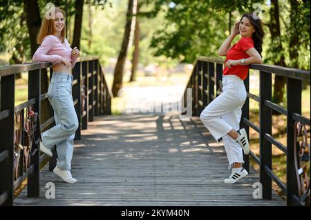 Ivano-Frankivsk, Ukraine 14. Juli 2022: Zwei Mädchen im Schulalter posieren auf einer Brücke für ihre gemeinsamen Porträts, Schulschießen. Stockfoto