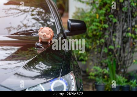 Sparschwein und Autoschlüssel auf der Motorhaube. Konzept von Autokrediten und Sparen. Stockfoto