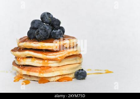 Ein Stapel Pfannkuchen, isoliert auf weißem Hintergrund mit frischen Blaubeeren und Sirup Stockfoto