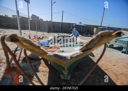 01. Dezember 2022, Palästinensische Gebiete, Stadt Gaza: Ein palästinensischer Handwerker repariert ein Fischerboot mit Glasfaser in einer von den Vereinten Nationen in Zusammenarbeit mit der Deutschen Agentur für internationale Zusammenarbeit im Hafen von Gaza beaufsichtigten Werkstatt. Israel erklärte sich bereit, die Einfuhr von Glasfasermaterial in den Gazastreifen zum ersten Mal seit 2007 zu gestatten, um Fischereifahrzeuge unter strenger internationaler Überwachung zu halten. Seit fast 15 Jahren wurde der Zugang zu gebrauchten Materialien in die palästinensische Enklave verboten, weil sie von palästinensischen Militärparteien in der militärischen Industrie verwendet wurden. Foto: M Stockfoto