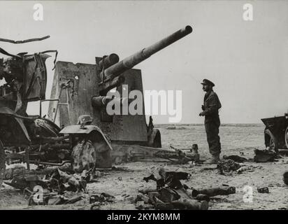 Vintage-Foto um den 1941. November eines britischen Armeeoffiziers, der das Wrack einer deutschen 88mm-Artilleriewaffe untersuchte, die im Zweiten Weltkrieg in Bir el Gubi in Nordafrika zerstört wurde Stockfoto