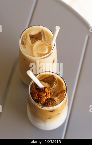 Kalter Kaffee Latte mit Milch im Glas auf dem Cafétisch der Stadt. Sommereisgetränke. Hochwertiges Foto Stockfoto