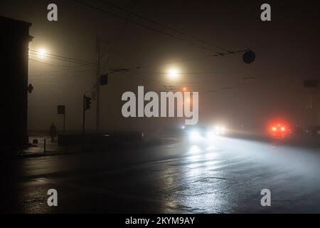 Die Straßen der ukrainischen Hauptstadt Kiew während des Verdunkelungsvorgangs werden von vorbeifahrenden Autos und einsamen Straßenlaternen vor dem Hintergrund von komplett dunklen Wohngebäuden beleuchtet. Seit Oktober 10 wurden in der Ukraine während der russischen Angriffe auf die Infrastruktur des Landes Notstromausfälle erzwungen. Die meisten Einwohner Kiews haben immer noch keinen Strom, da Ingenieure um die Wiederherstellung der Versorgung kämpfen, nachdem russische Raketen das Energienetz des Landes durchbohrten. Die Arbeiter der Versorgungsunternehmen arbeiteten noch daran, die Heizung und das Wasser wieder anzuschließen, als die Temperaturen in Kiew auf null zurückgingen Stockfoto