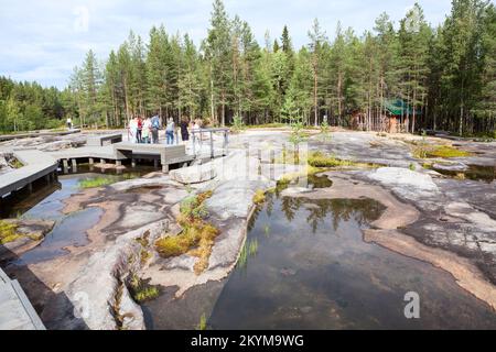 Zalavruga, Stadt Belomorsk, Republik Karelien, Russland-circa Aug. 2022: Touristen mit einem Reiseleiter sind im Bereich der archäologischen Anlage mit dem Weißen Stockfoto