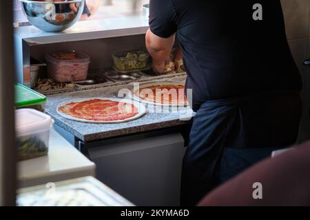 Unverkennbarer Mann, der in einer Restaurantküche Pizza zubereitet. Stockfoto