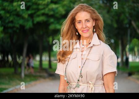 Outdoor-Porträt von lächelnden reifen blonden und blauäugigen Frau. Stockfoto