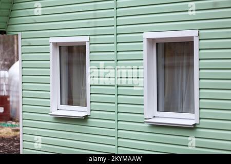 Zwei Plastikfenster an der Fassade des Hauses. Nebengleise Stockfoto