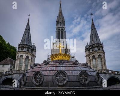 Die Kirchen und das Dach mit dem goldenen Kreuz der neobyzantinischen Basilika Notre Dame de Lourdes im Süden Frankreichs Stockfoto