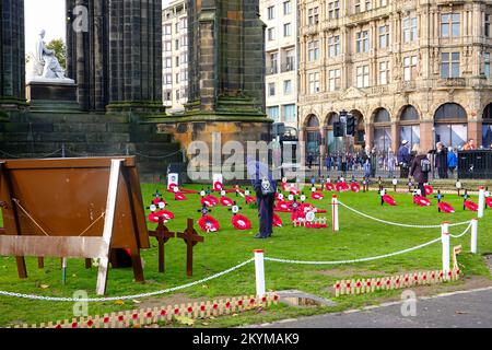 Ein Mann, der Kränze ansieht, im Garden of Remembrance, um die Toten zu ehren und an die Lebenden zu erinnern, Princes Street Gardens, Edinburgh, Schottland, Großbritannien. Stockfoto